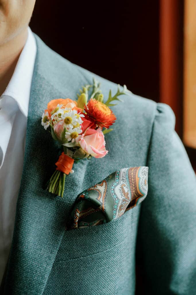 Flowers on Groom's lapel consisting of daisies, strawflower and roses in white, yellow, pink and orange