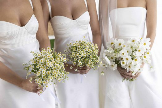 Bridal party in all white carrying their white mono bloom bouquets.